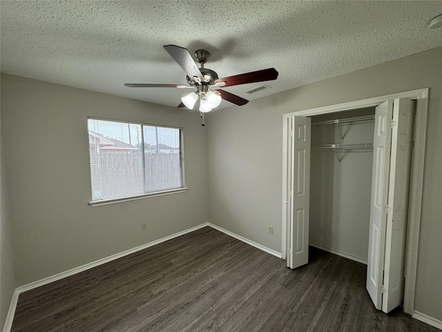 unfurnished bedroom with dark wood-type flooring, ceiling fan, a closet, and a textured ceiling