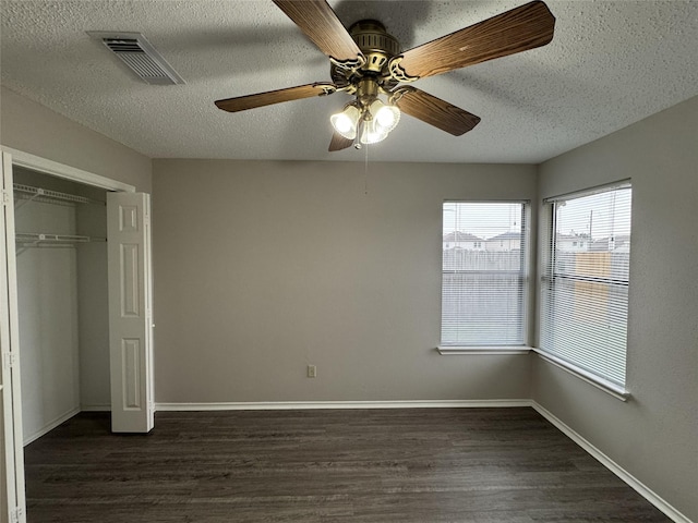 unfurnished bedroom featuring ceiling fan, a closet, dark wood-type flooring, and a textured ceiling