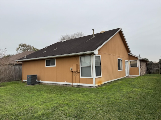 back of house with cooling unit and a lawn