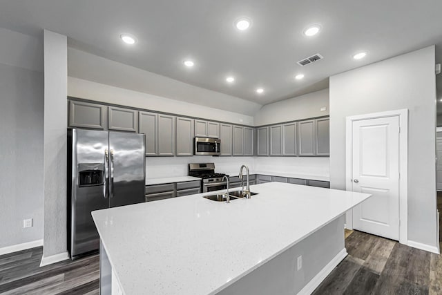 kitchen featuring stainless steel appliances, dark hardwood / wood-style floors, a kitchen island with sink, vaulted ceiling, and sink