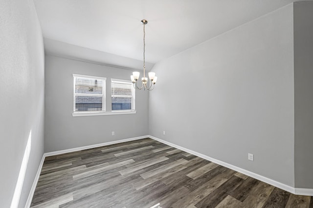 spare room with dark wood-type flooring and an inviting chandelier