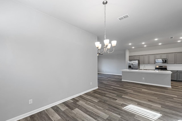 kitchen with pendant lighting, a kitchen island with sink, gray cabinetry, stainless steel appliances, and a chandelier