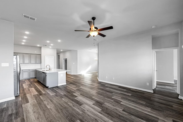 kitchen featuring sink, a kitchen island with sink, stainless steel refrigerator, ceiling fan, and gray cabinetry