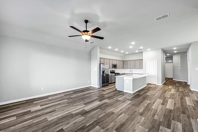 kitchen with a center island with sink, ceiling fan, stainless steel appliances, dark hardwood / wood-style flooring, and sink