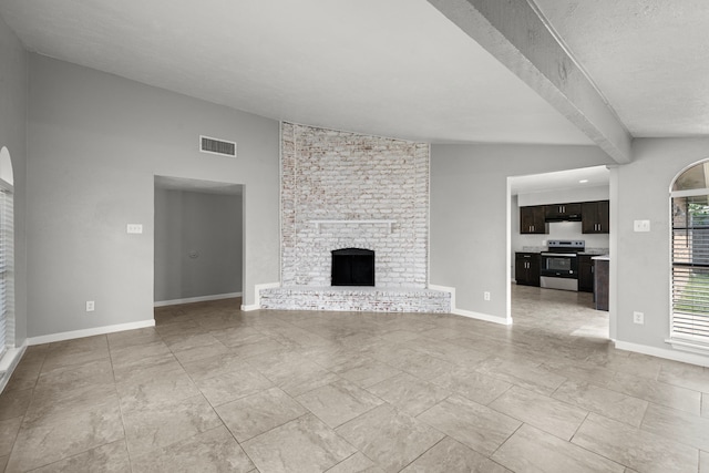 unfurnished living room featuring a brick fireplace, a textured ceiling, and lofted ceiling