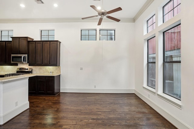 kitchen with appliances with stainless steel finishes, dark hardwood / wood-style flooring, decorative backsplash, ornamental molding, and dark brown cabinets