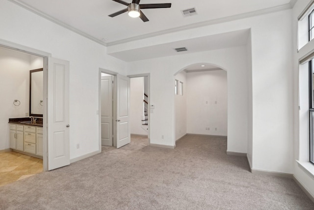 unfurnished bedroom featuring ceiling fan, connected bathroom, light colored carpet, ornamental molding, and sink