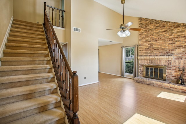 unfurnished living room with ceiling fan, light hardwood / wood-style flooring, high vaulted ceiling, and a fireplace