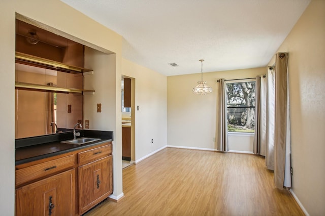 kitchen featuring light hardwood / wood-style floors, sink, hanging light fixtures, and an inviting chandelier