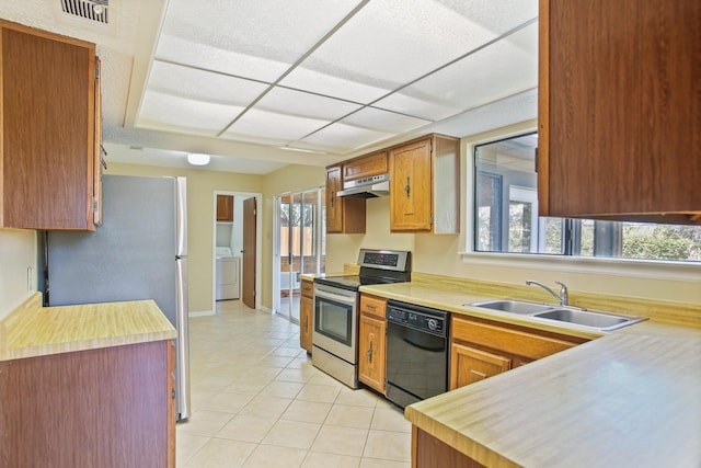 kitchen with sink, appliances with stainless steel finishes, washer / dryer, and light tile patterned flooring