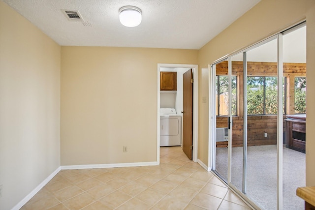 unfurnished room featuring a textured ceiling, light tile patterned floors, and washer / clothes dryer