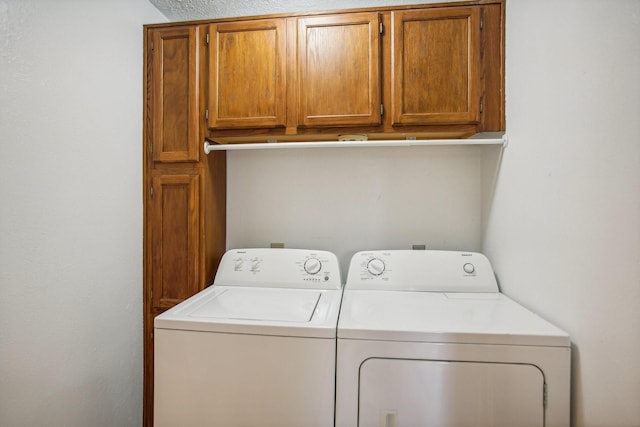 laundry room featuring separate washer and dryer, a textured ceiling, and cabinets