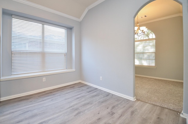 empty room with vaulted ceiling, an inviting chandelier, ornamental molding, and light hardwood / wood-style flooring