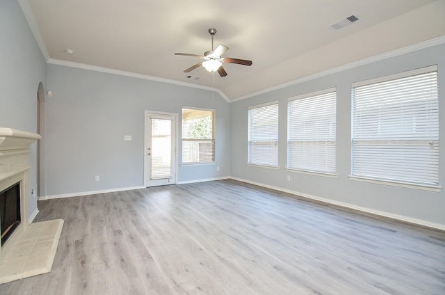 unfurnished living room featuring lofted ceiling, ornamental molding, light wood-type flooring, ceiling fan, and a tiled fireplace