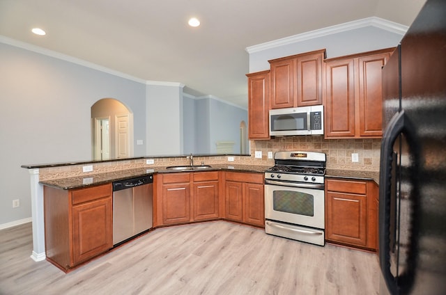 kitchen featuring sink, appliances with stainless steel finishes, crown molding, and dark stone countertops