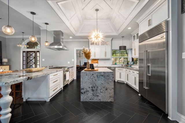 kitchen featuring light stone countertops, extractor fan, white cabinetry, hanging light fixtures, and high quality appliances