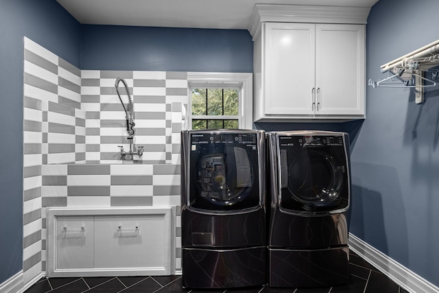 clothes washing area with cabinets, dark tile patterned flooring, and washer and clothes dryer