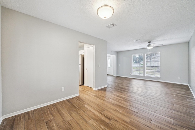 empty room featuring ceiling fan, light wood-type flooring, and a textured ceiling