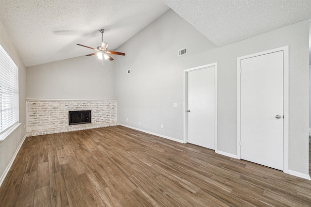 unfurnished living room featuring lofted ceiling, ceiling fan, a fireplace, wood-type flooring, and a textured ceiling