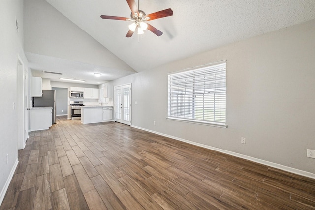 unfurnished living room with hardwood / wood-style floors, ceiling fan, french doors, high vaulted ceiling, and sink