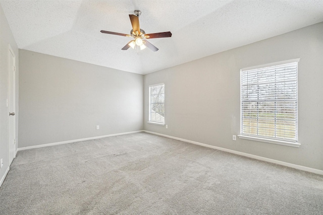 empty room featuring ceiling fan, a wealth of natural light, light carpet, and a textured ceiling