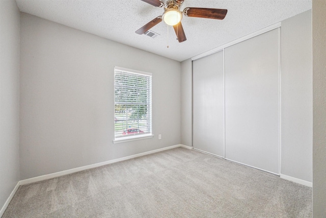 unfurnished room featuring a textured ceiling, ceiling fan, and light colored carpet