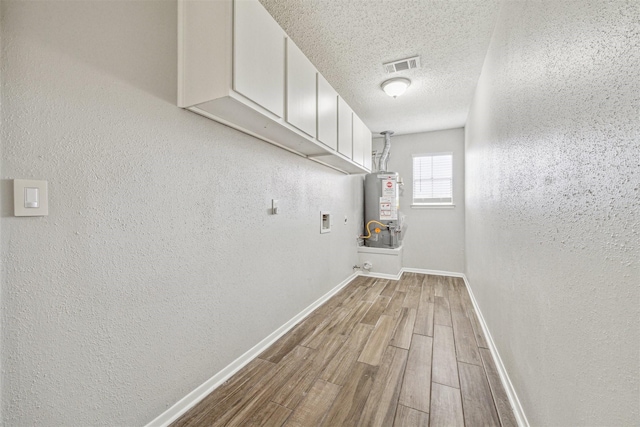 laundry room with a textured ceiling, cabinets, hookup for a washing machine, and gas water heater