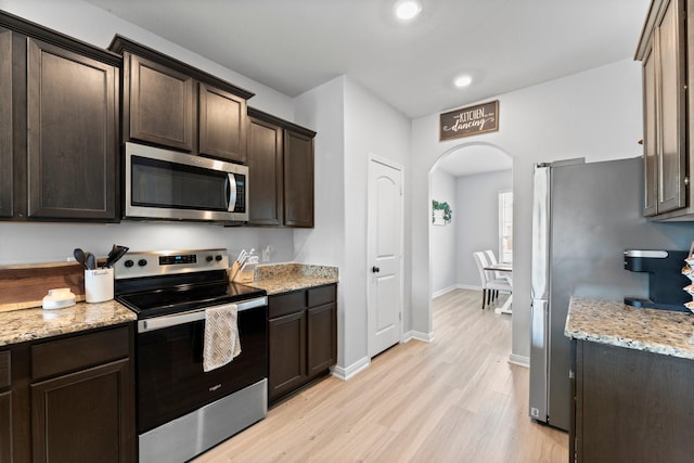 kitchen featuring light stone countertops, light hardwood / wood-style flooring, stainless steel appliances, and dark brown cabinets