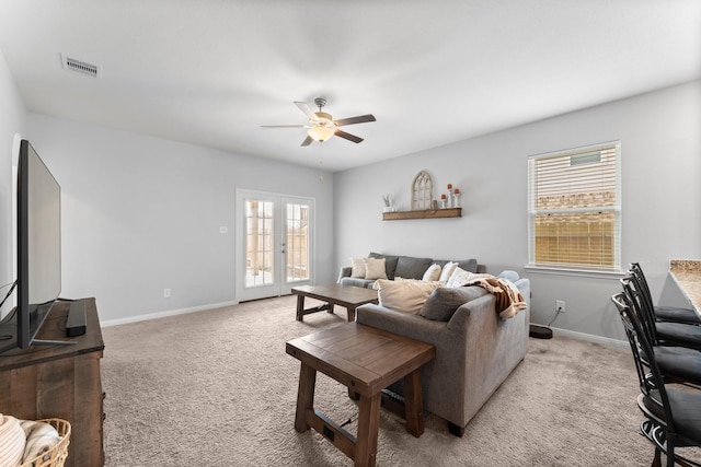 living room featuring ceiling fan, light colored carpet, and french doors