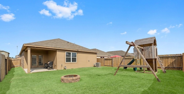 back of property featuring a playground, an outdoor fire pit, a yard, and a patio