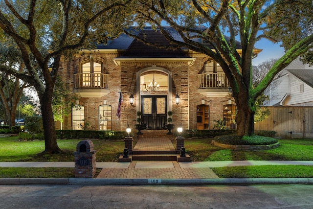 view of front of house featuring a front lawn, french doors, and a balcony