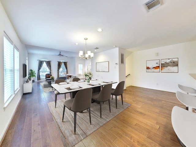 dining area featuring ceiling fan with notable chandelier and wood-type flooring