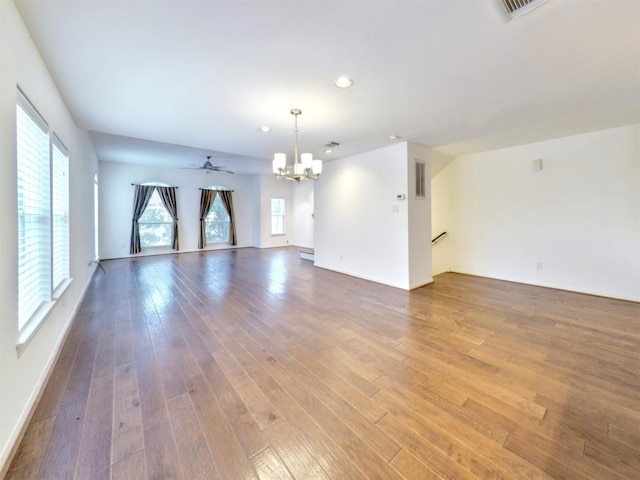 empty room with ceiling fan with notable chandelier and wood-type flooring