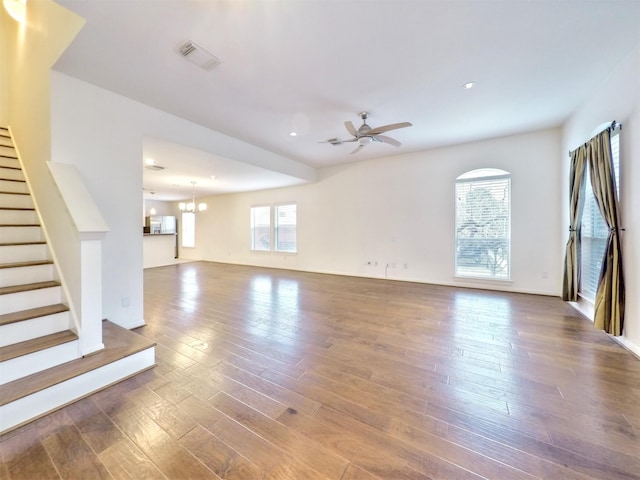 unfurnished living room with ceiling fan with notable chandelier and hardwood / wood-style flooring