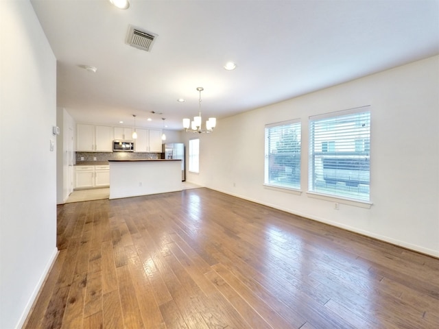 unfurnished living room featuring light hardwood / wood-style flooring and an inviting chandelier