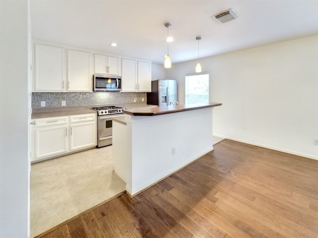 kitchen featuring white cabinetry, appliances with stainless steel finishes, a kitchen island with sink, and hanging light fixtures