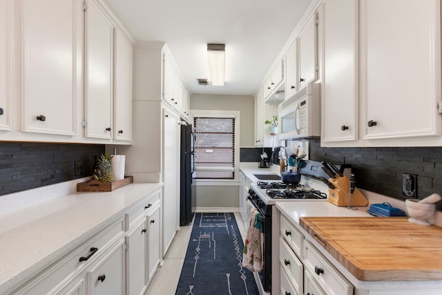 kitchen with white cabinets, decorative backsplash, and gas stove