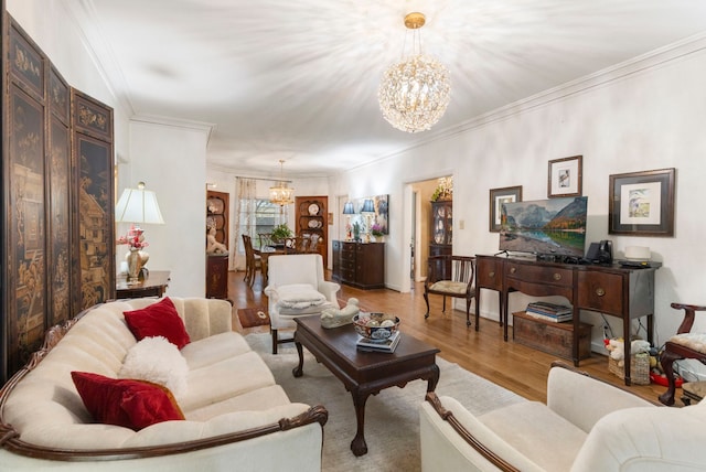 living room featuring crown molding, a chandelier, and light wood-type flooring