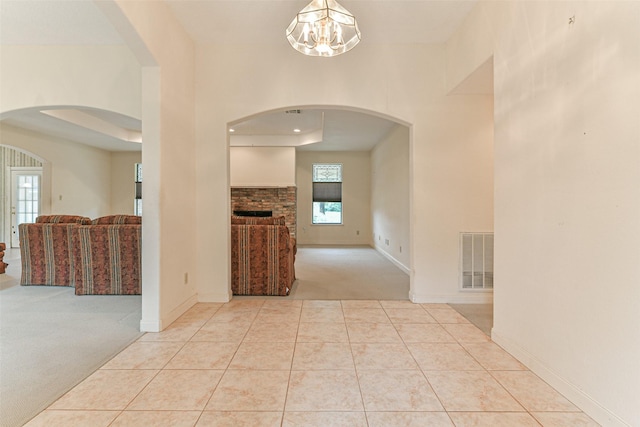 hallway with light carpet and an inviting chandelier