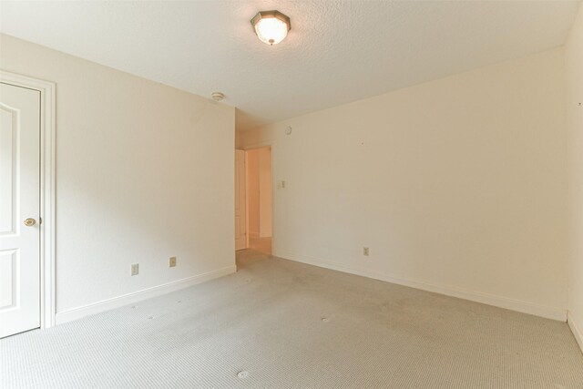 unfurnished room featuring light colored carpet and a textured ceiling