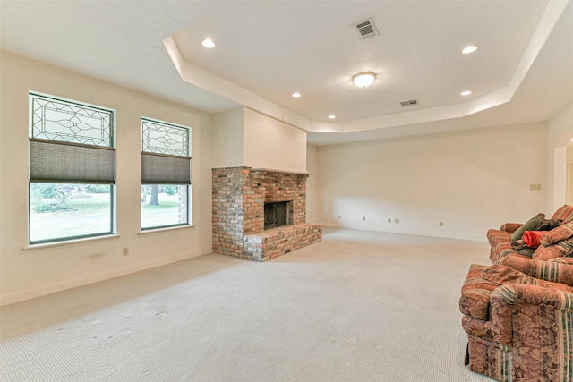 living room featuring light colored carpet, a fireplace, and a tray ceiling