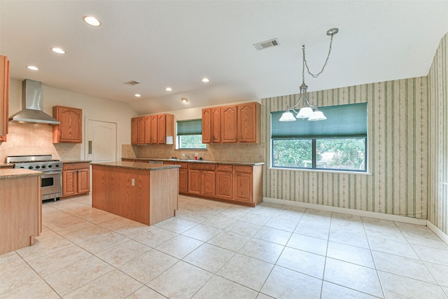 kitchen with pendant lighting, high end range, a center island, wall chimney exhaust hood, and a chandelier