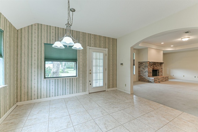 unfurnished dining area with light colored carpet, a notable chandelier, and a brick fireplace