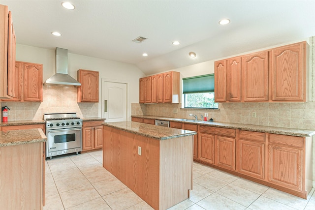 kitchen with appliances with stainless steel finishes, a center island, wall chimney range hood, light tile patterned flooring, and light stone counters