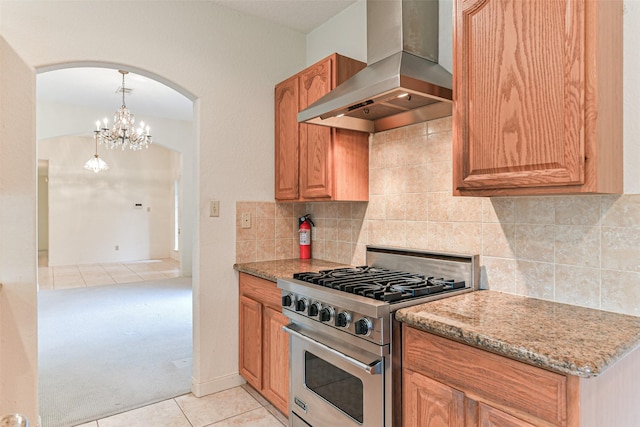 kitchen featuring wall chimney exhaust hood, decorative light fixtures, stainless steel range, an inviting chandelier, and light tile patterned floors