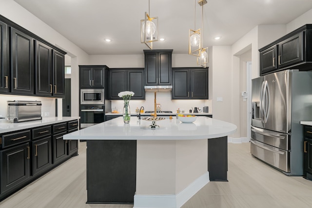 kitchen featuring hanging light fixtures, appliances with stainless steel finishes, and a center island with sink