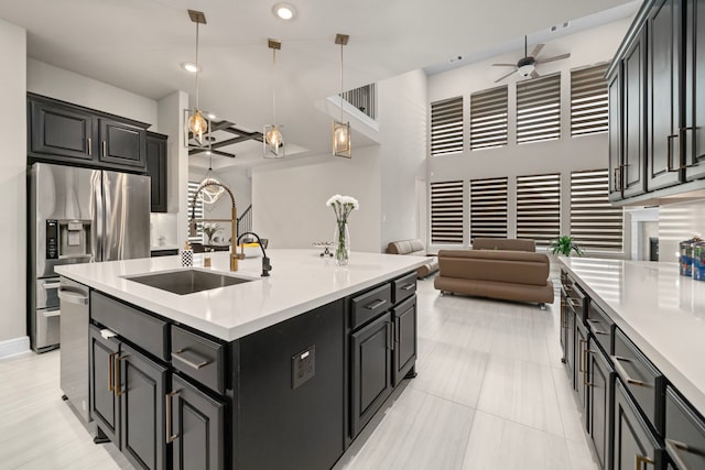 kitchen with decorative light fixtures, sink, a center island with sink, and ceiling fan