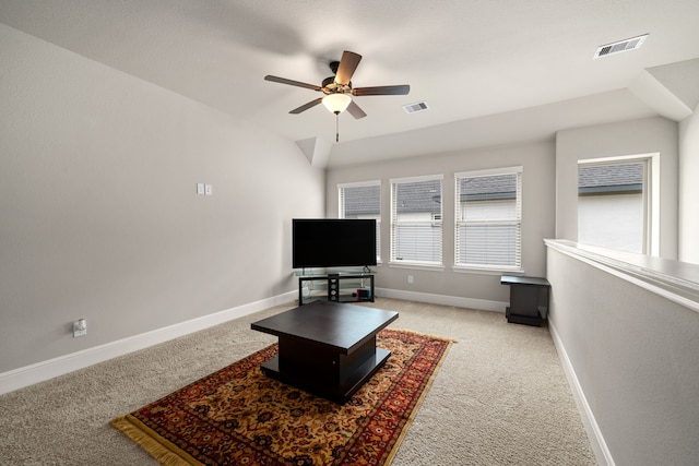 carpeted living room with ceiling fan and vaulted ceiling