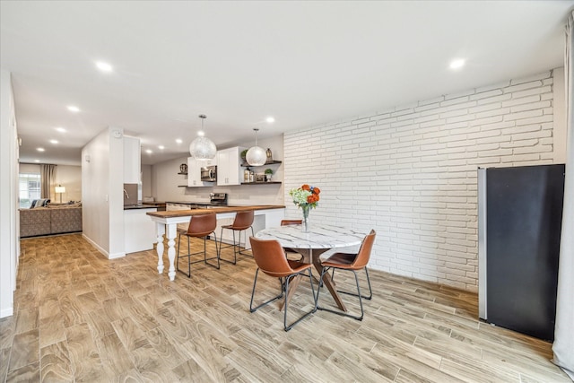 dining room featuring brick wall and light hardwood / wood-style flooring