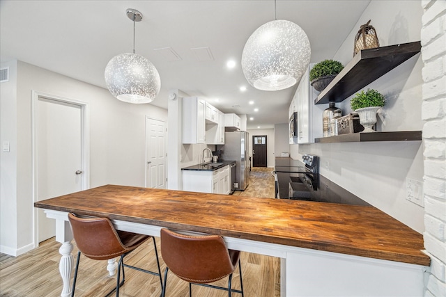 kitchen with white cabinetry, appliances with stainless steel finishes, butcher block counters, and kitchen peninsula